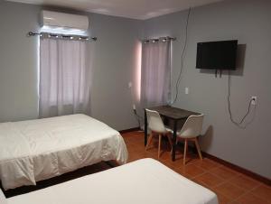 a room with two beds and a table and a television at Hill Garden Resort Hotel in San Ignacio