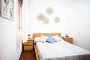 a bedroom with a bed with white sheets and blue pillows at Bonito apartamento en primera línea de playa in Motril