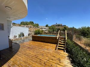 a wooden deck with a swimming pool next to a house at Har-Adir B&B in Ḥurfeish