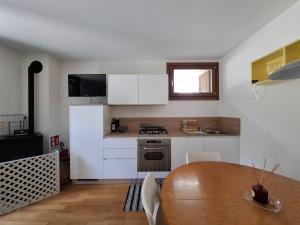 a kitchen with a wooden table and white cabinets at Casa al Dos in Cavedago