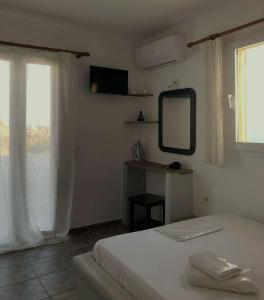 a bedroom with a bed and a mirror and a window at Aegean Sunset in Kionia