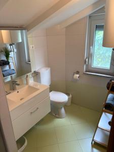 a bathroom with a toilet and a sink and a window at Apartment Maja in Dobrinj