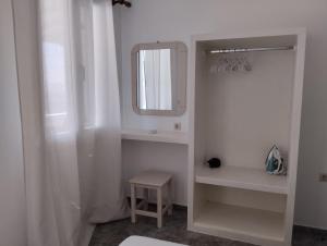 a white bathroom with a mirror and a stool at Aegean Sunset in Kionia +26 photos