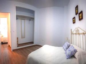 Un dormitorio blanco con una cama y un espejo. en Apartment in Peñaflor with Charming Patio, en Peñaflor