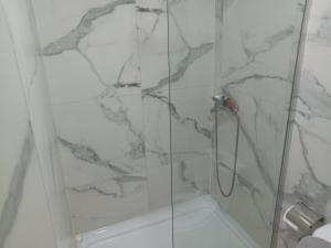 a bathroom with a shower with a marble wall at Urban Square in Kumanovo +5 photos