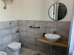 Un baño con lavabo, inodoro y espejo. en Casa Mia, en Villamassargia