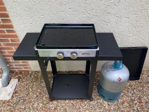 a barbecue grill with a water bottle next to a wall at Nature luxuriante, jeux en famille, workation et Sauna pour 1 à 4 personnes in Labosse