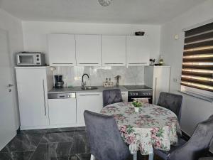 a kitchen with a table and chairs and a kitchen with white cabinets at Deluxe House Aqua Una in Otoka