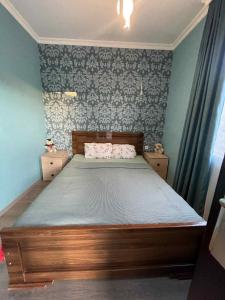 a bedroom with a bed with a wooden frame and wallpaper at Guest House in Racha Almagi in Ambrolauri