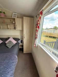 a small bedroom with a bed and a window at Andreas Fir Trees Retreat at 7 Lakes Country Park in Crowle