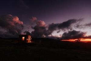 a small house in a field with a sunset at É diferente, descubra por quê in Urubici