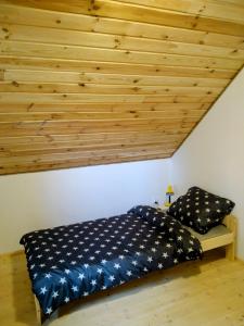 a bed in a room with a wooden ceiling at Agroturystyka Kozianka in Iława