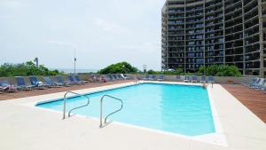 a swimming pool with chairs and a large building at Green Sea Suite at High Point North in Ocean City