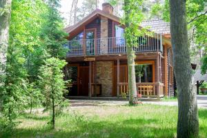 a log cabin in the woods with a balcony at Kotwica Morska in Pobierowo
