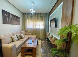 a living room with a couch and a table at Luxury Modern Studio with Netflix, Kitchen and Free Parking Elite Garden, Marrakesh in Aït Saïd