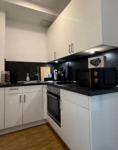 a kitchen with white cabinets and a black wall at Gemütliches Apartment nähe HBF-City--Lift in Hannover