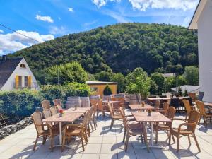 a patio with tables and chairs with a mountain in the background at Rheinliebe Bistro und Pension in Lorch am Rhein