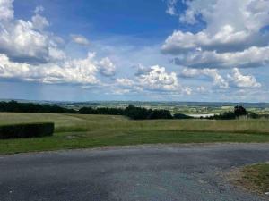 La Celle-sous-GouzonにあるEntre Lot et Dordogne maison 10 personnes avec piscineの曇り空の野原にある空いている道