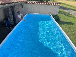 La Celle-sous-GouzonにあるEntre Lot et Dordogne maison 10 personnes avec piscineの青いスイミングプールの横に立つ男