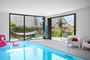 a house with a swimming pool with chairs and a hammock at Les Villas Majolie - Villa 13 Océan - 5 étoiles in Combrit
