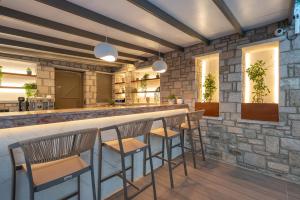 a bar with stools in front of a stone wall at Alysos Luxurious Apartments in Myrina