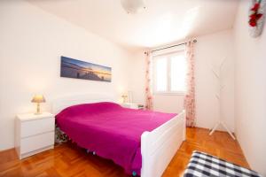 a bedroom with a large bed with a purple blanket at Casa Mimosa Bright and Soulful in Budva