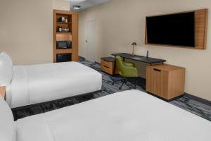 a hotel room with a bed and a desk with a television at Fairfield by Marriott Inn & Suites Stockton Lathrop in Lathrop
