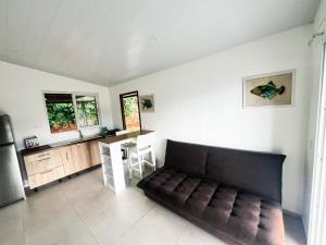 Una sala de estar con un sofá y una cocina. en Blue House Lodge, en Faaa