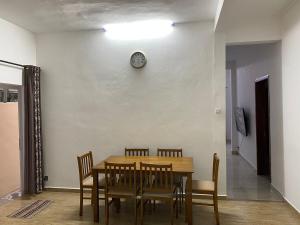 a dining room table with chairs and a clock on a wall at Maison de Pagoda in Port Louis