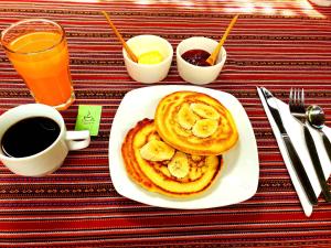 a plate of pancakes with bananas on a table with a cup of coffee at Hospedaje K'uchuwasi in Ollantaytambo