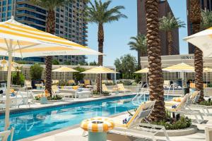 ein Pool mit Stühlen und Sonnenschirmen und Palmen in der Unterkunft Fontainebleau Las Vegas in Las Vegas