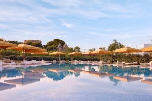 a pool with orange umbrellas and chairs and tables at Cala Ponte, a Tribute Portfolio Hotel in Polignano a Mare