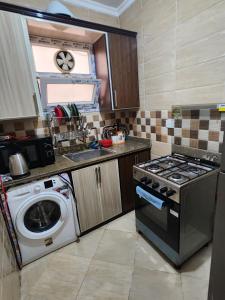 a kitchen with a stove and a washing machine at العالمين in El Alamein