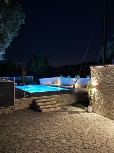 a swimming pool in a backyard at night at Paxos Dream House in Vlachopoulátika