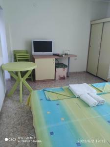 a room with a bed and a table and a tv at стаи за гости Левтерови in Chernomorets
