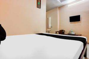 a bedroom with a bed and a tv on the wall at Hotel O Woodlands in Kurnool