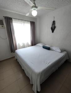 a bedroom with a bed with a ceiling fan and a window at Departamento SOL in Ixtapa +15 photos