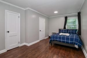 une chambre avec un lit bleu, des murs blancs et du parquet dans l'établissement The Gilead Cottage Near Lake Tillery & Uwharrie, à Mount Gilead