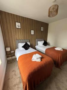 a hotel room with two beds with orange sheets at Stylish apartment in the City Centre in Spinney Hill +24 photos