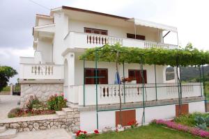 a white house with a balcony and flowers at Apartments in Lopar - Insel Rab 17729 in Lopar