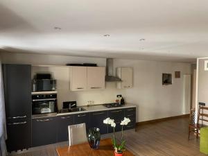 a kitchen with black cabinets and a table with flowers at Aosta Center large Apartment with large shower in Aosta