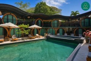 a swimming pool with chairs and umbrellas next to a building at Saranda Boutique Hotel in Puerto Viejo