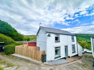 ein weißes Haus mit einem Zaun davor in der Unterkunft Brecon beacons Cottage with Cinema Room sleeps 5 in Pont Sticill