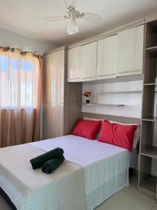 a bedroom with a bed with red pillows on it at Apartamento 100 metros da praia com piscina in Ilhéus