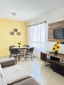a living room with a table and chairs and a television at Apartamento 100 metros da praia com piscina in Ilhéus