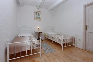 two beds in a room with white walls and wooden floors at Family friendly house with a swimming pool Grizane, Crikvenica - 24302 in Grižane +19 photos