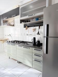 a white kitchen with a stainless steel refrigerator at Apartamento 100 metros da praia com piscina in Ilhéus