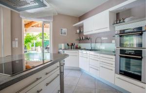 a kitchen with white cabinets and a large window at Cadre Nature in Montauroux