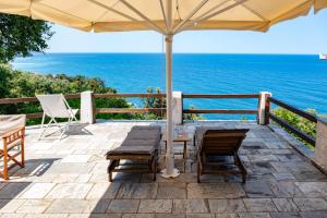 een patio met een parasol en stoelen en de oceaan bij Hideaway in Damouchari with private access to sea ANNA's HORIZON in Damouchari