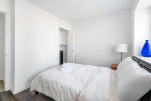 a white bedroom with a bed and a blue vase at Bright and Cozy Home in Quiet Neighborhood in Vancouver